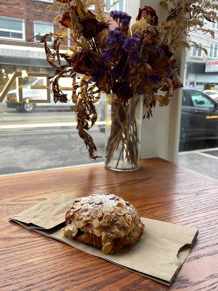 Almond croissant on brown paper with toasted almonds and powdered sugar by the window